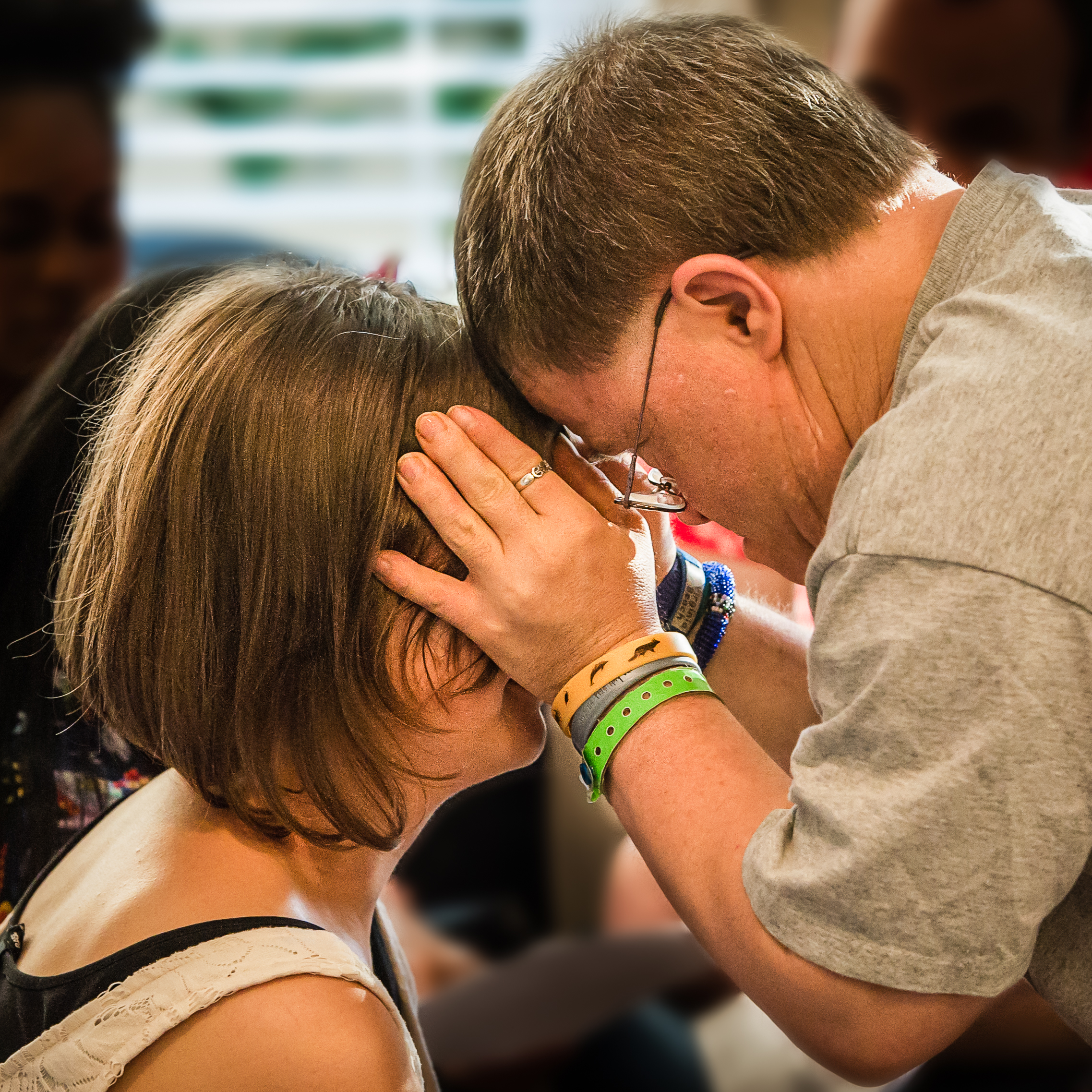 A man puts his hands and forehead against a woman's forehead to bless her.