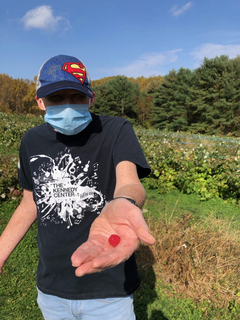 Person in hat holds a berry in his hand
