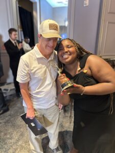 Ricky and Grace posing with an Emmy statue for On Loneliness's award in Societal Concerns