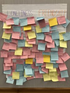 Colorful sticky notes fill a larger paper with written reflections on what loneliness and friendship smell and taste like.